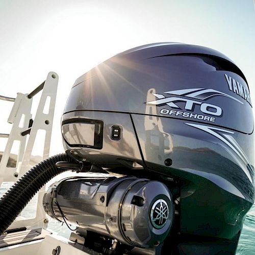 The image features a Yamaha XTO Offshore boat motor mounted on the back of a boat with sunlight reflecting off its surface in a marine setting.